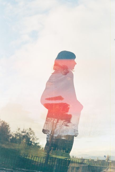 A creative double exposure film photo of a woman with a dreamy, nostalgic vibe.