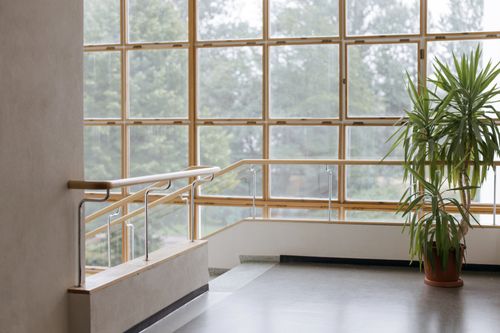 Free Spacious interior staircase with large grid windows, modern railing, and potted plant. Stock Photo