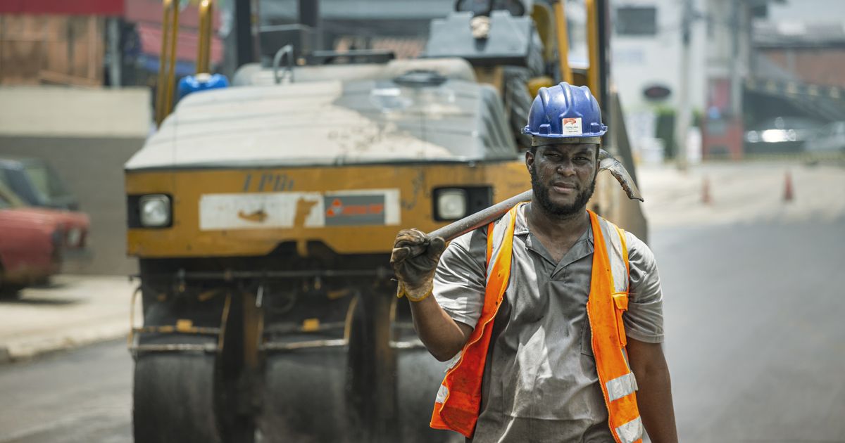 Trabalhador da construção civil com equipamentos de segurança trabalhando na rua em Cotia, Brasil. Uma cena que retrata a atividade de construção urbana.