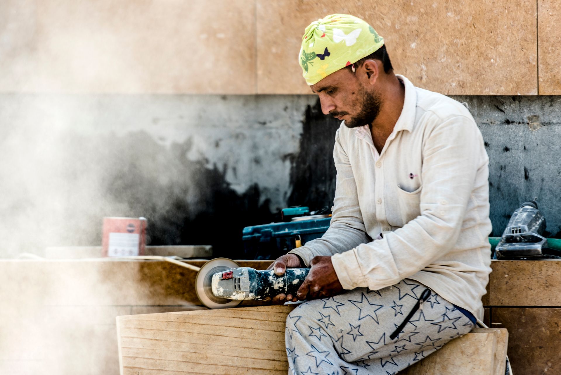 A carpenter uses a grinder in a dusty woodworking shop. Safety gear worn.
