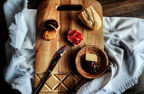 A Piece of Bread with Delicious Strawberry Jam on Wooden Chopping Board