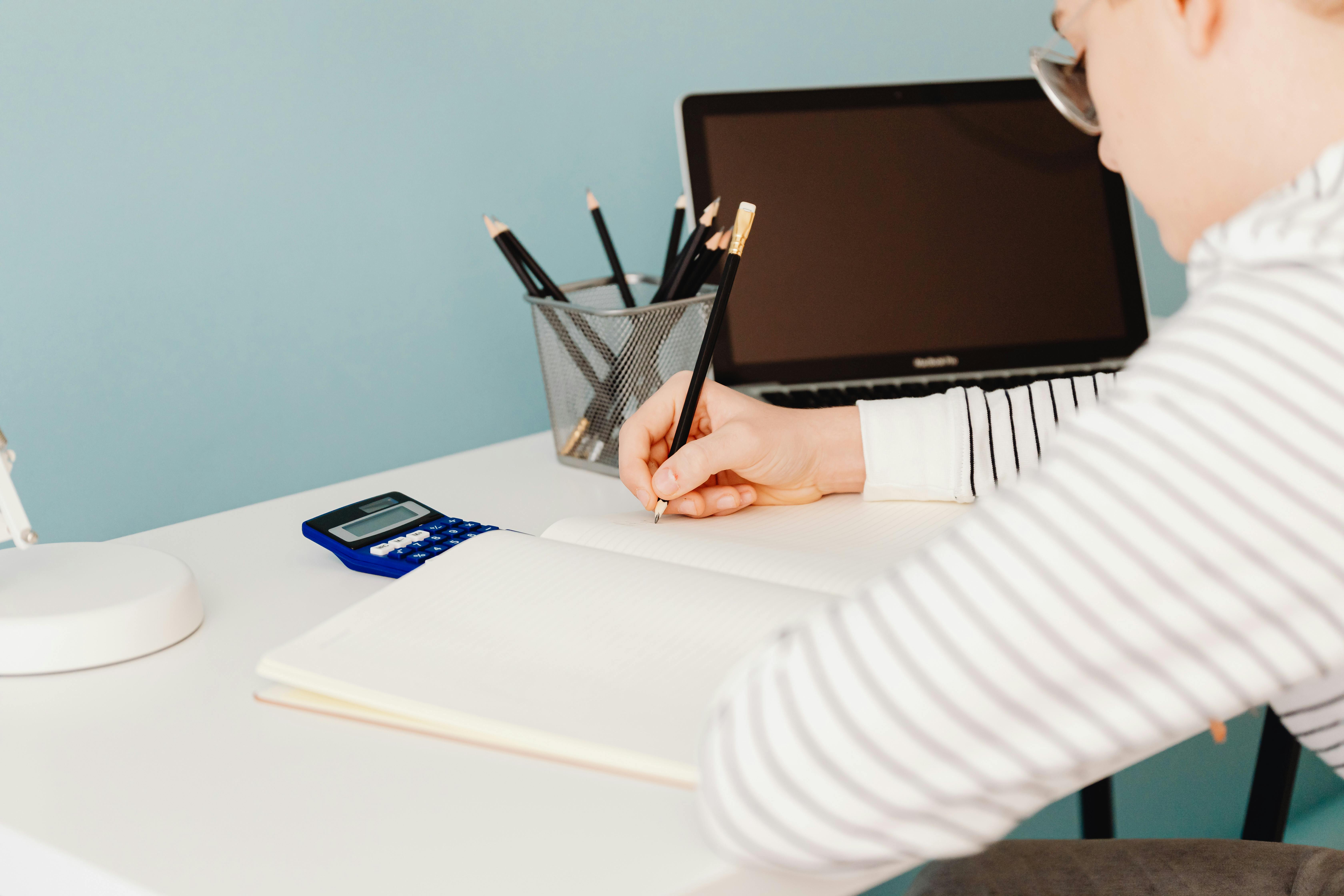 a person writing on white notebook