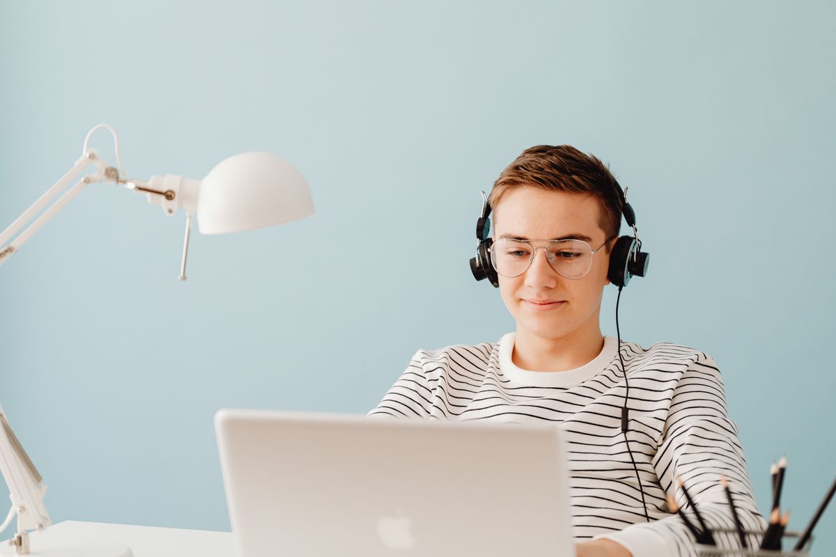 Un apprenant suit un module de formation en ligne sur son ordinateur, casque sur les oreilles