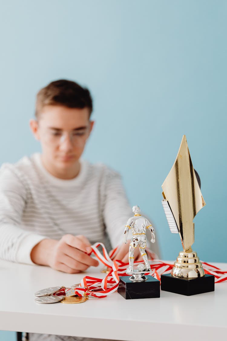 Guy With Prizes And Medals On Table