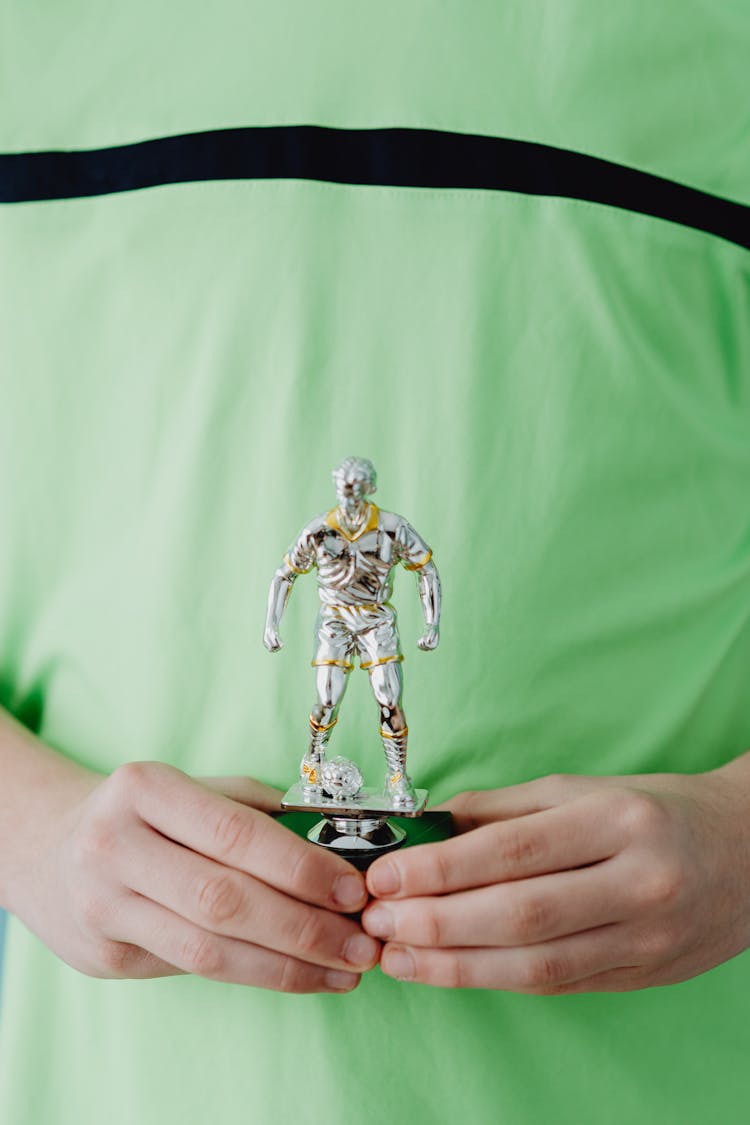 Boy Holding A Football Cup In A Shape Of A Man 