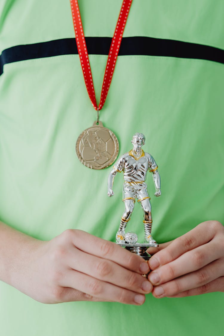 Person With A Medal Holding A Trophy