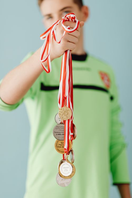 Free Teen wearing sports jersey displays multiple medals, representing achievement and success. Stock Photo
