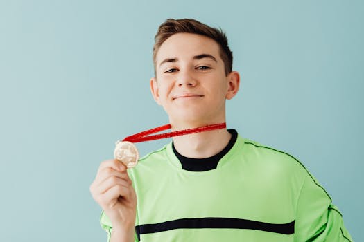 Young man smiling proudly while holding a medal in a studio setting.