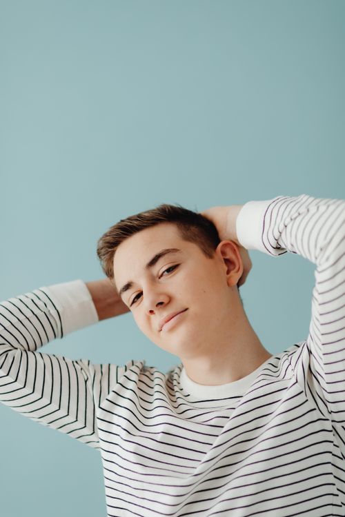 Free A relaxed portrait of a young man posing against a blue backdrop indoors. Stock Photo