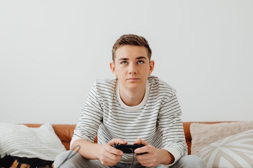 Teenage Boy Sitting on a Couch and Playing Video Games 