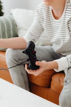 Teen boy holding a game controller while playing video games indoors.
