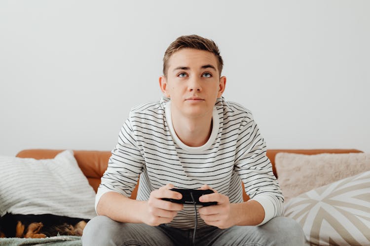 Teenage Boy Sitting On A Couch And Playing Video Games 