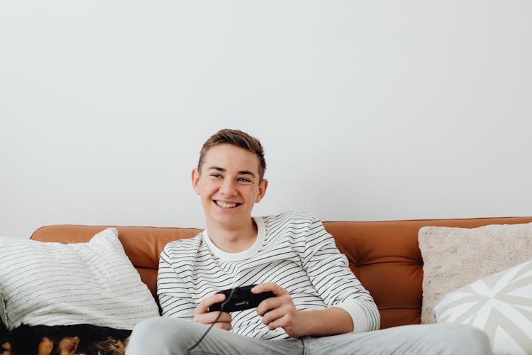Smiling Guy Relaxing At Home Playing Console
