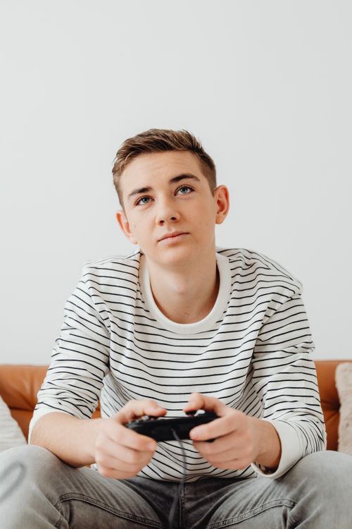 Free A relaxed teenager playing video games at home with a game controller. Stock Photo