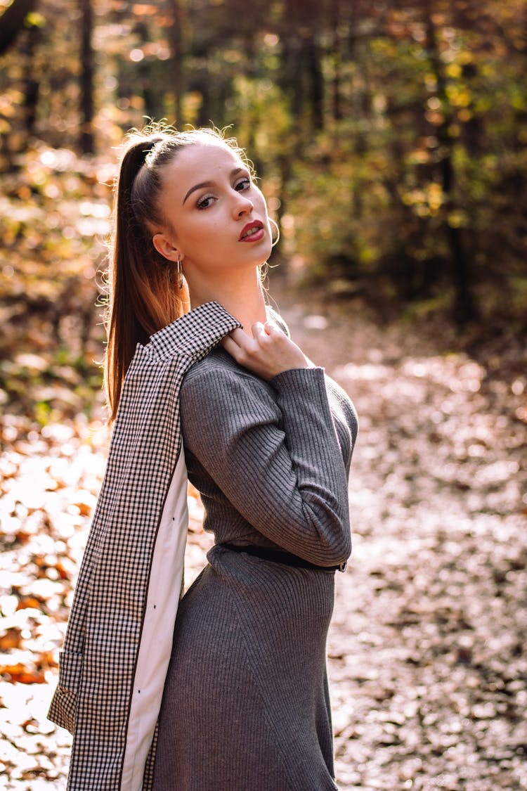 Young Woman In A Dress And With A Blazer Thrown Over Her Shoulder Posing Outdoors 