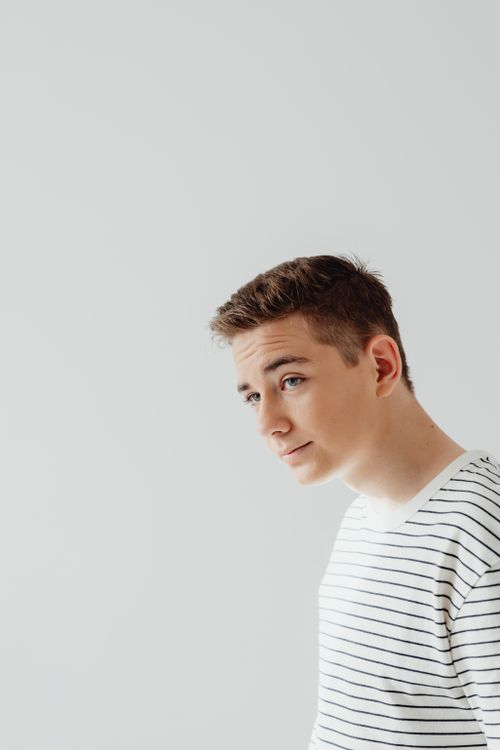 Free Portrait of a young teenager in a striped blouse against a plain backdrop. Stock Photo