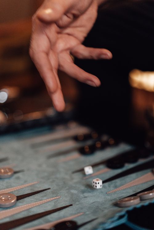 Free Crop faceless male player throwing dice while playing gambling backgammon board game at pastime Stock Photo