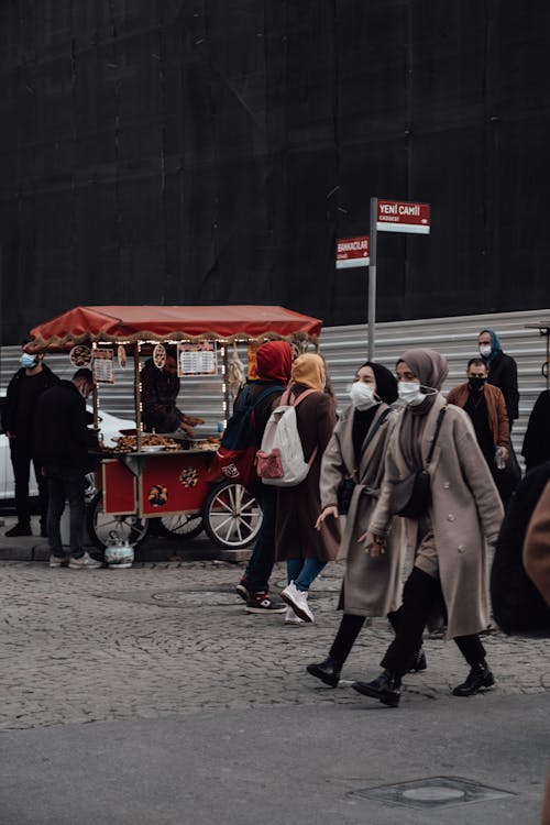 Free Crowded street with people in masks and warm clothes walking against street food cart Stock Photo