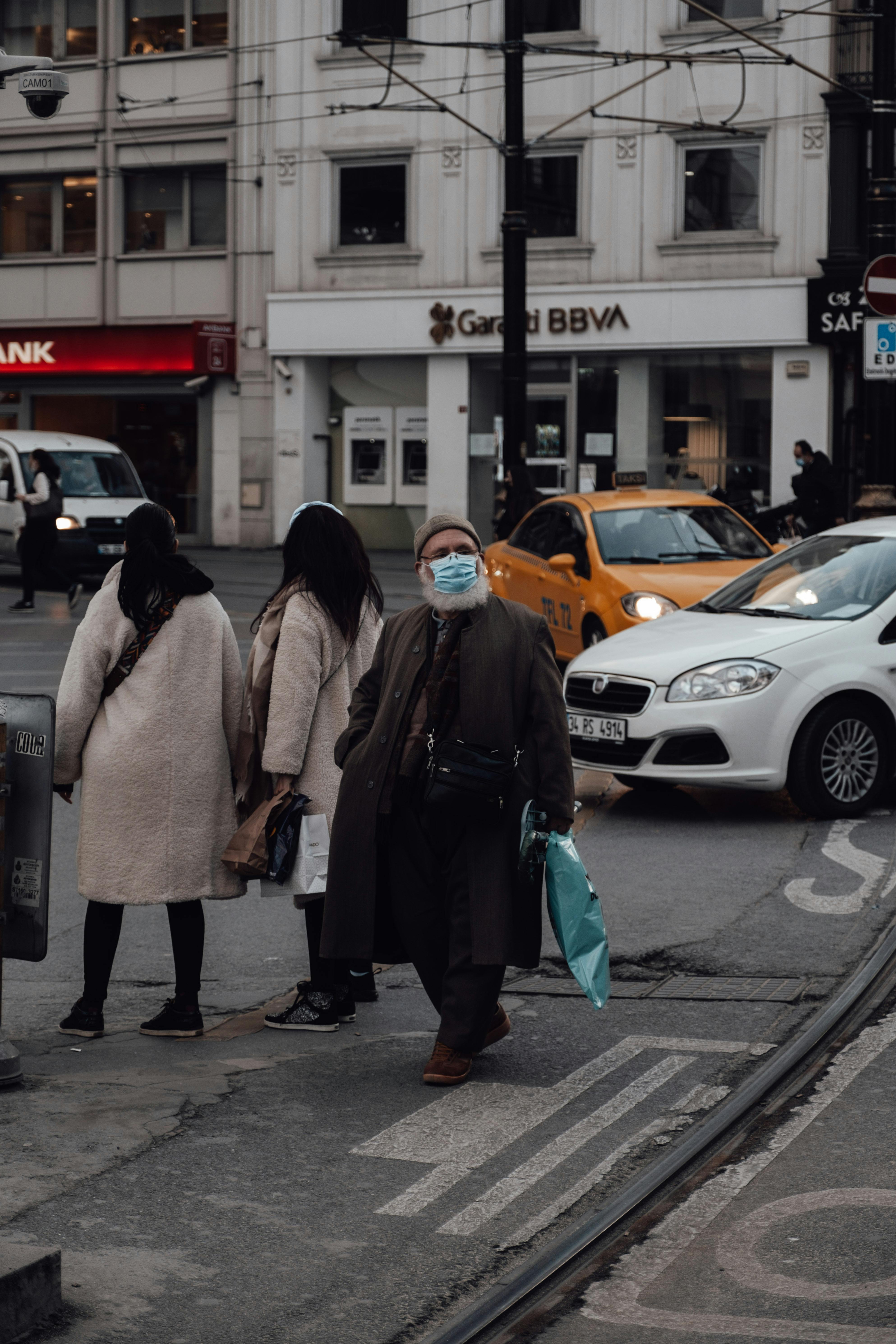 pedestrians on sidewalk of road with cars