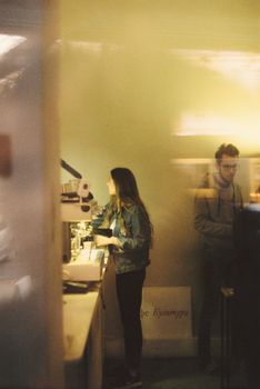Two young adults engaged in a science exhibit, viewing specimens under a microscope.