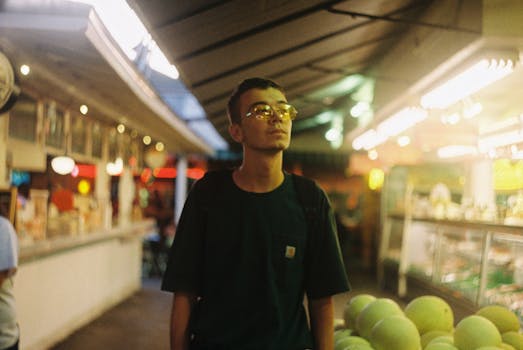 A young man exploring a vibrant indoor food market under warm lighting.