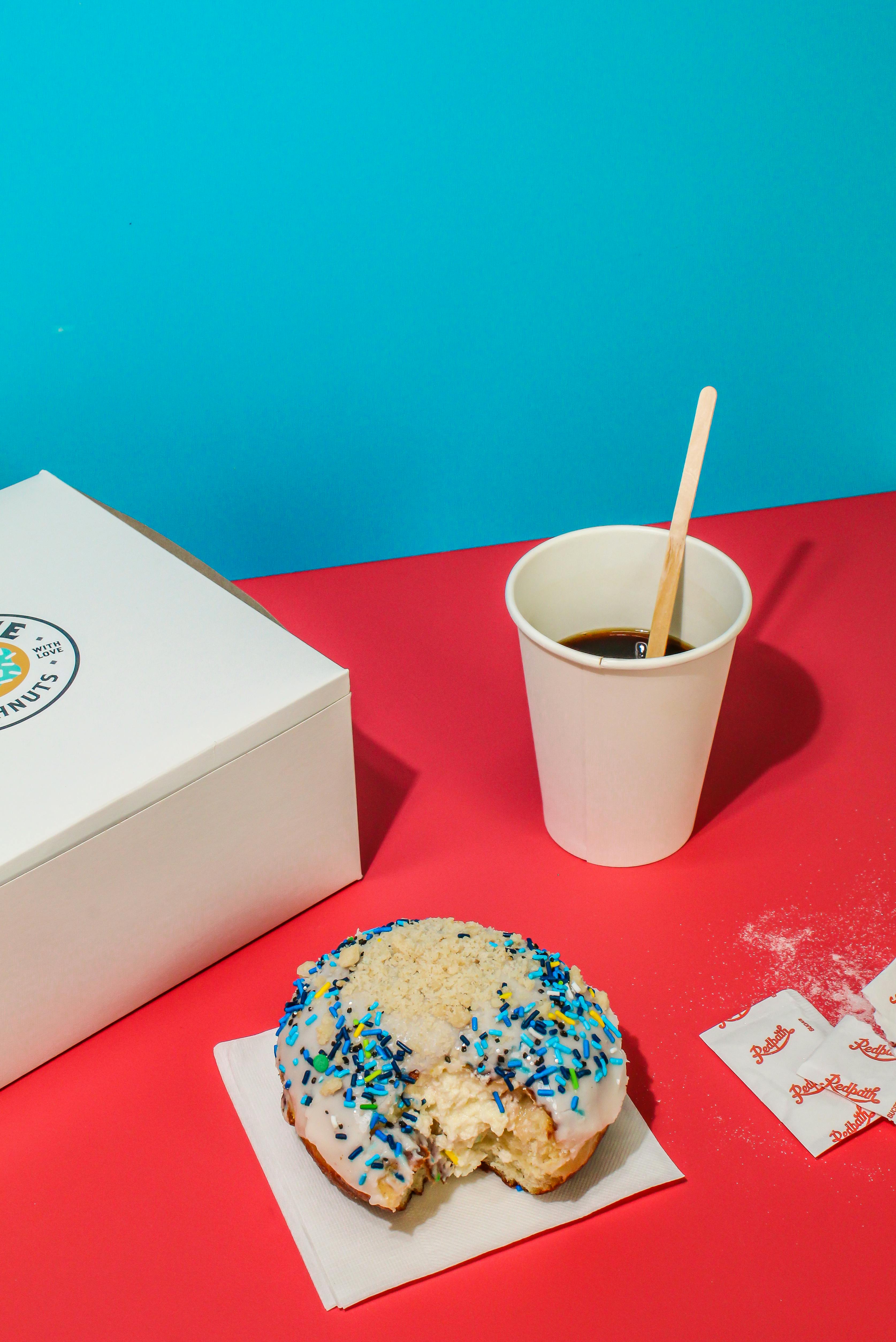 Vibrant scene of a donut with coffee on colorful background, ideal for food photography.