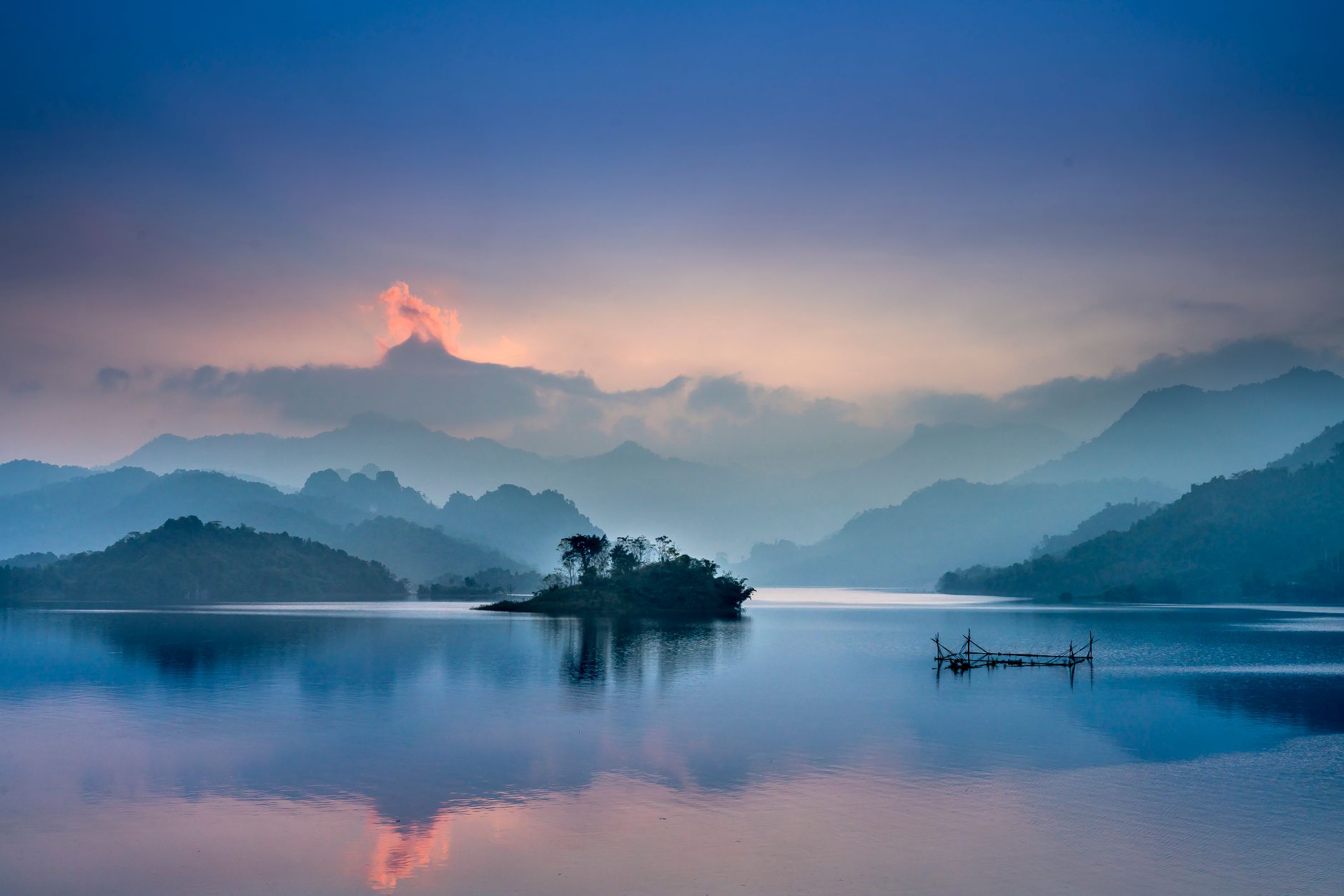 Peaceful lake scene at sunrise with misty mountains in Tuyên Quang, Vietnam.