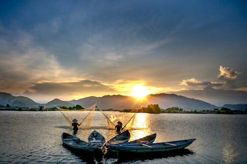 Two People Fishing on the Ocean during Sunset