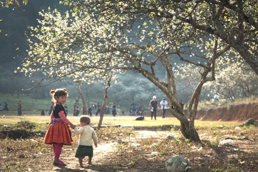 Children in colorful traditional attire in a blooming landscape in Son La, Vietnam.