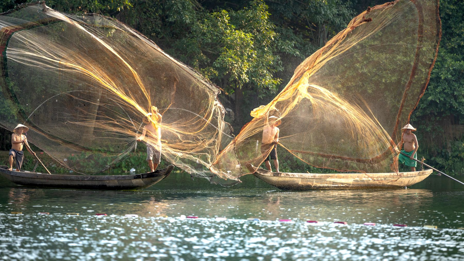 Scenic view of Vietnamese fishermen casting wide nets on a tranquil river.