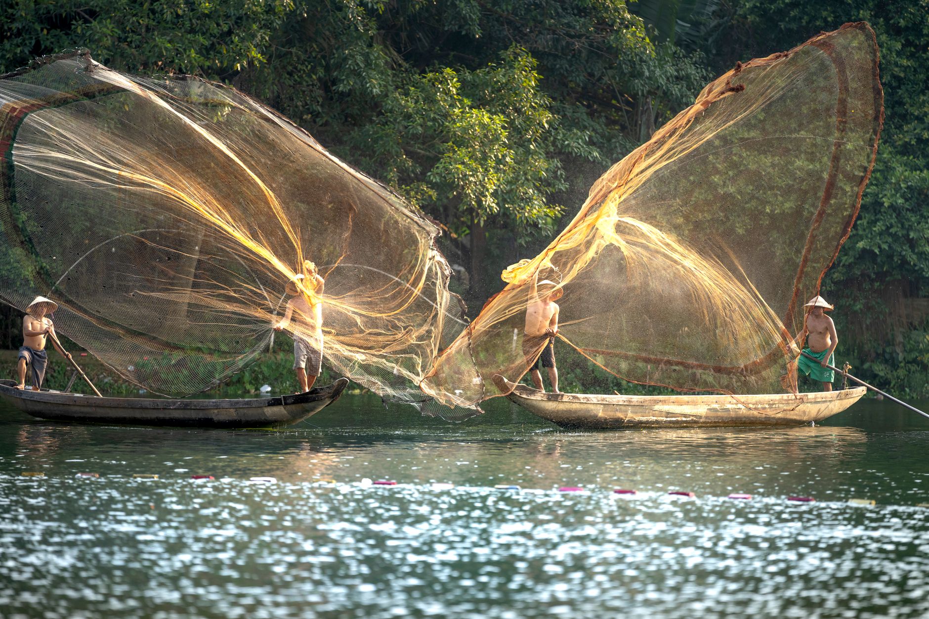 Scenic view of Vietnamese fishermen casting wide nets on a tranquil river.