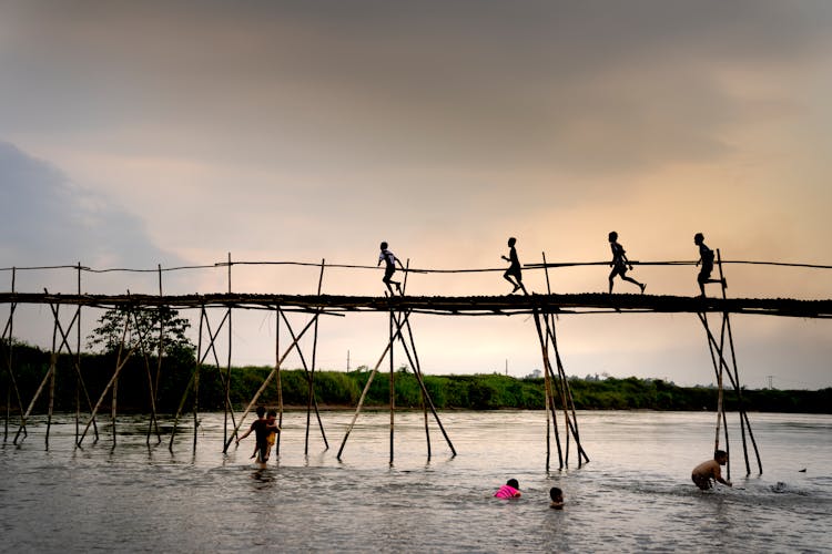 Silhouette Of Kids Running On The Wooden Bridge