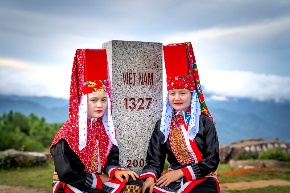 Two women in traditional Vietnamese attire pose at a historic boundary marker in Quảng Ninh, Vietnam.