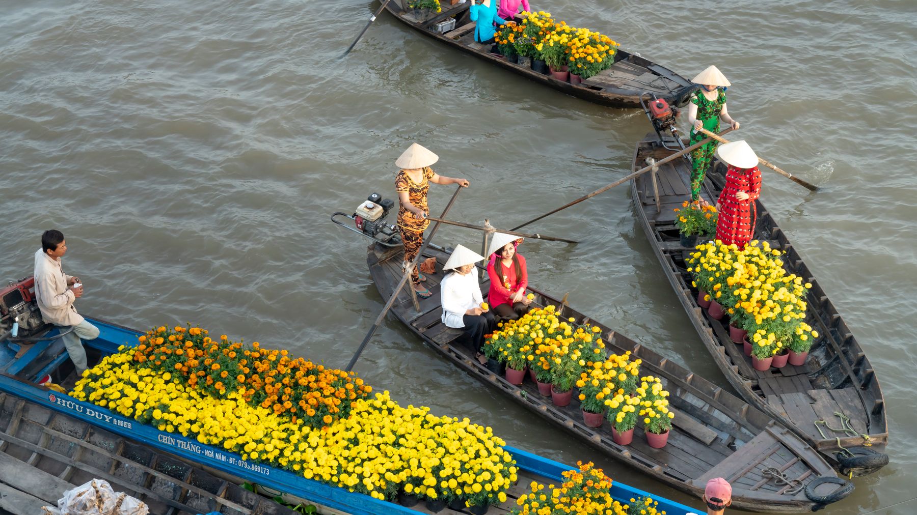 Colorful boats with flowers and vendors at Sóc Trăng floating market in Vietnam.