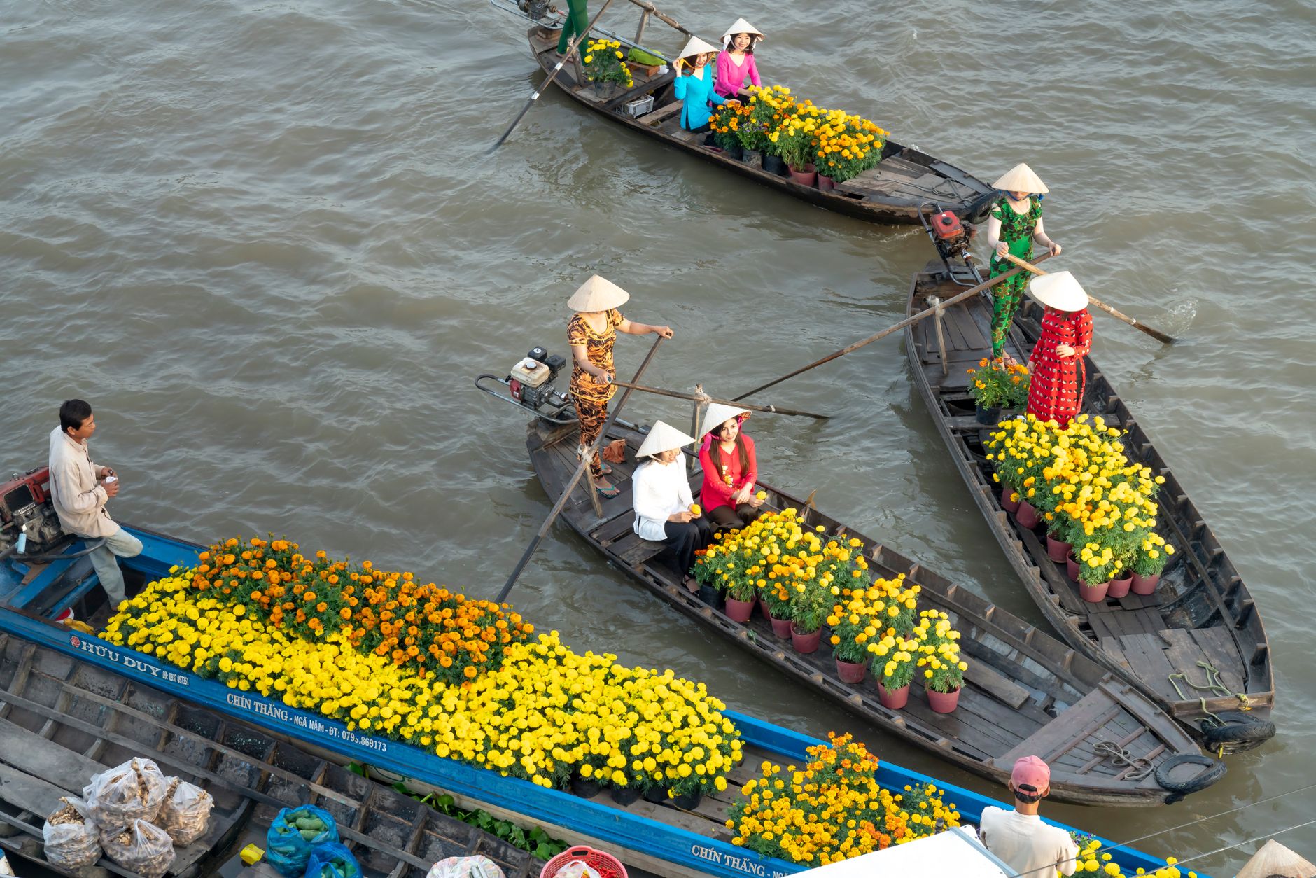 Colorful boats with flowers and vendors at SΓ³c TrΔng floating market in Vietnam.