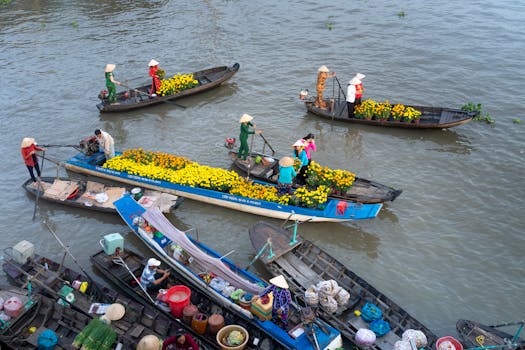 Colorful floating market with boats filled with flowers on a river in Soc Trang, Vietnam.