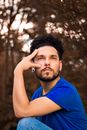 Thoughtful young bearded male in casual outfit with gauged ears touching face and looking away
