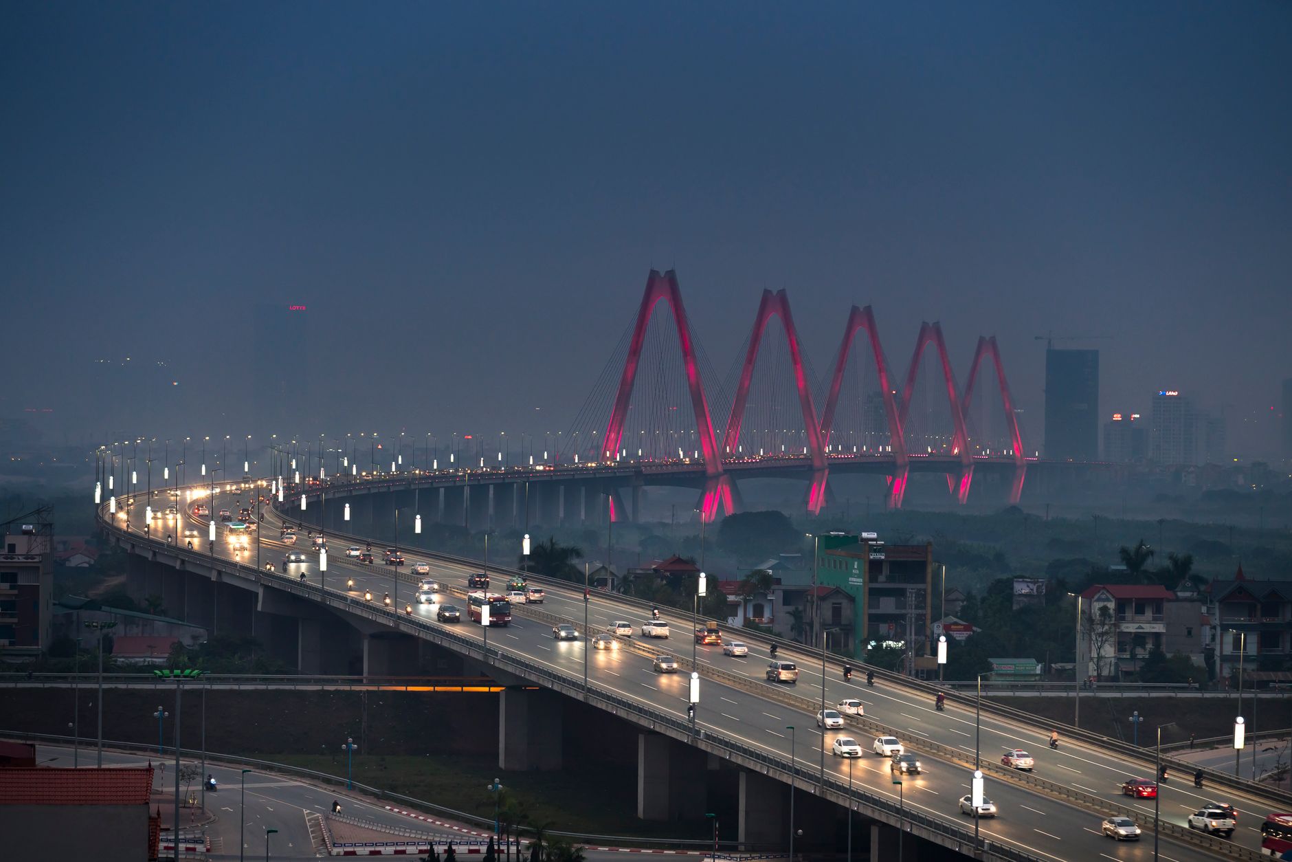 Dramatic aerial view of Hanoi's Nhat Tan Bridge at night, glowing with lights.