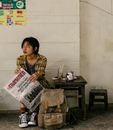 Ethnic female traveler with backpack and newspaper near wall