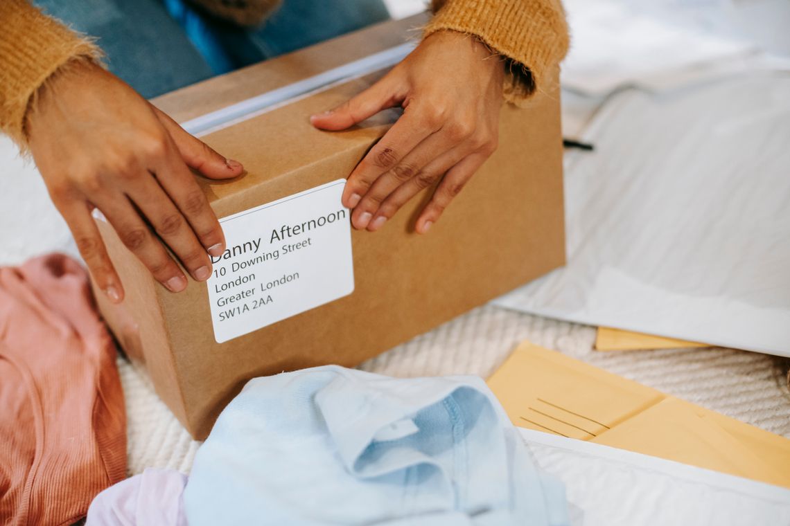 Hands preparing a parcel inside a cardboard box for shipping