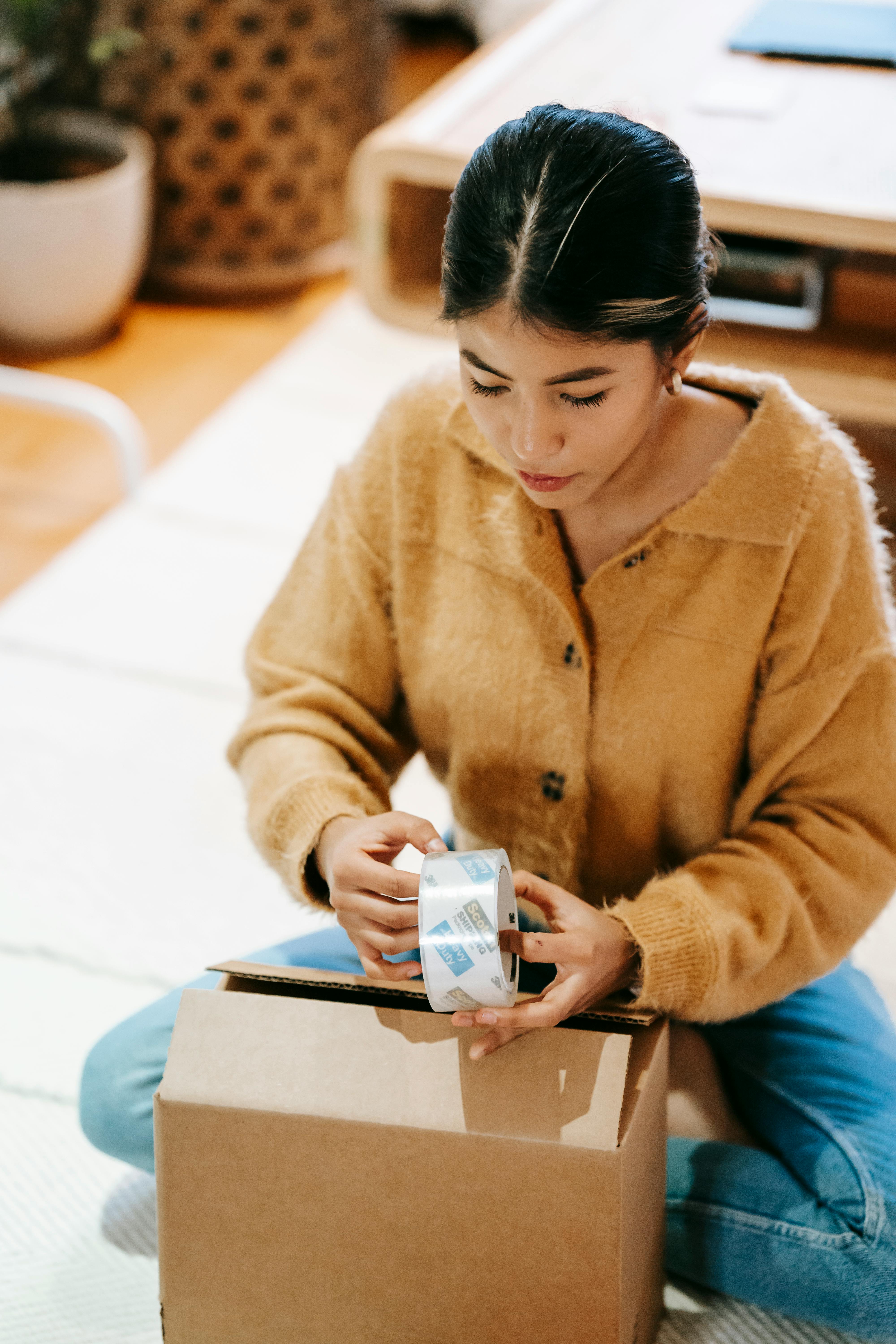 woman with adhesive tape packing parcel