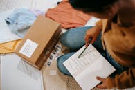 Woman comparing information in notebook and carton box