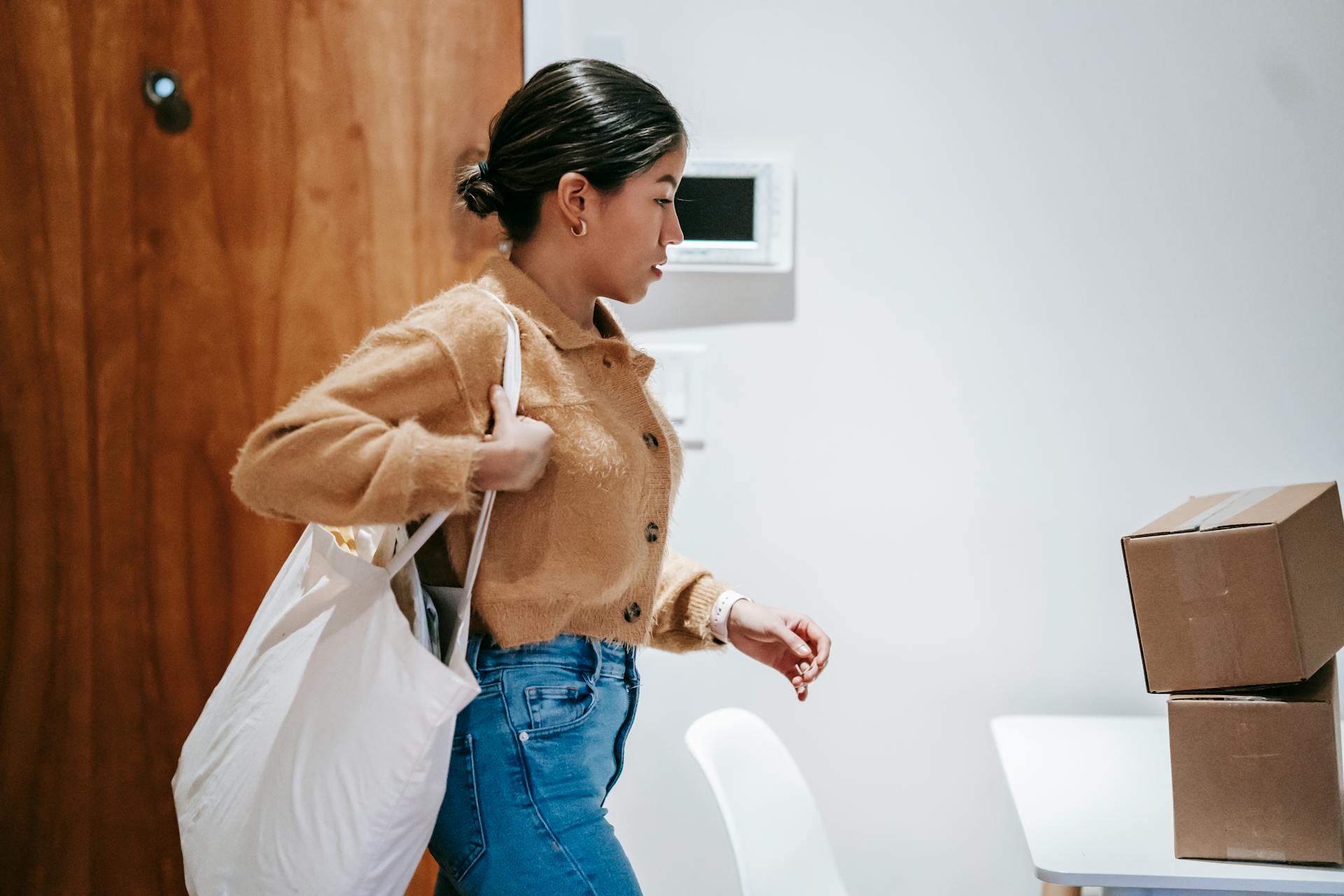 Focused delivery woman with boxes and shopping bag