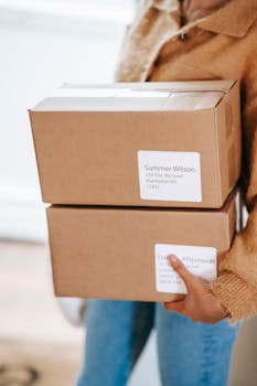 Woman holding cardboard boxes with shipping labels indoors, showcasing delivery service.