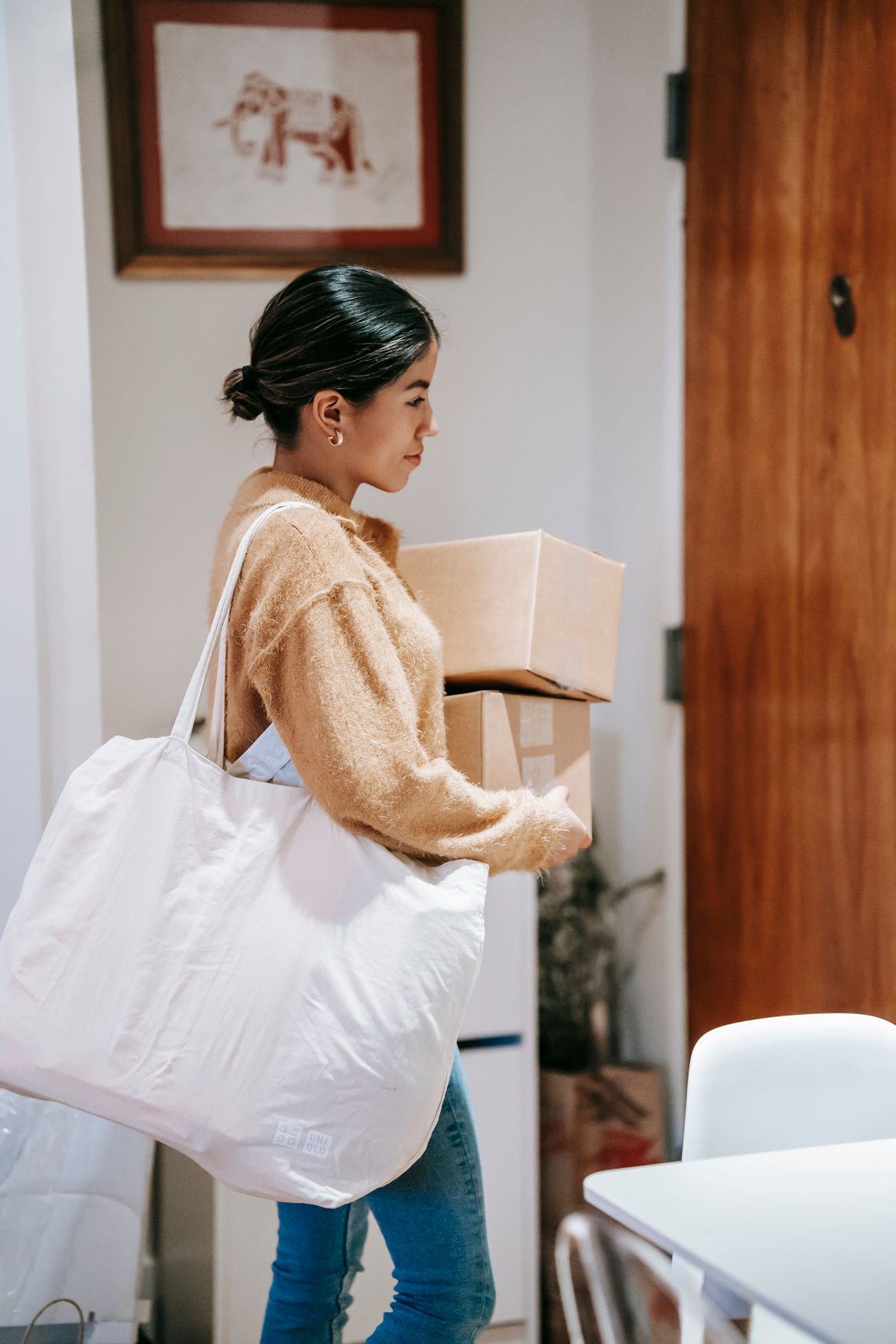 Smiling woman carrying delivery packages indoors, with her face clearly visible