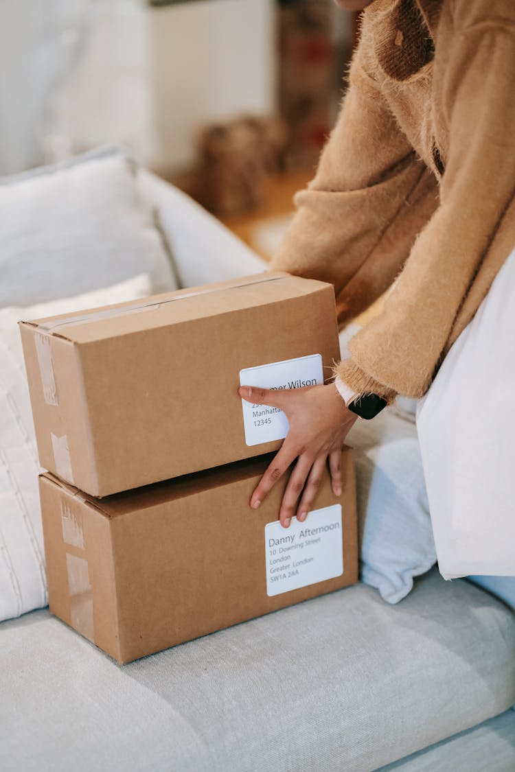 Woman Stacking Carton Boxes On Sofa In Apartment