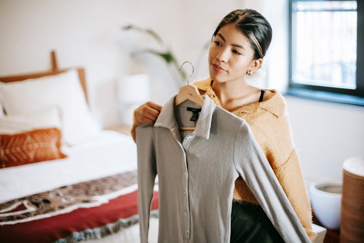 Asian Woman Trying On Clothes In Bedroom