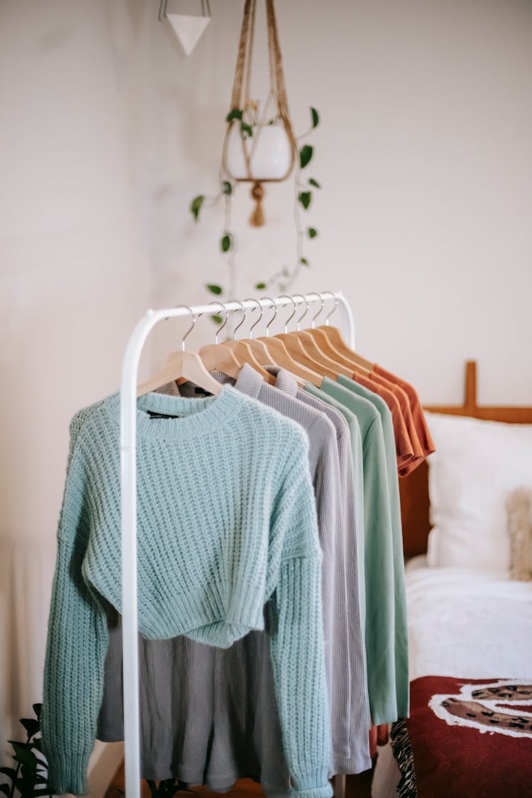 Wardrobe With Clothes On Hangers Near Bed At Home