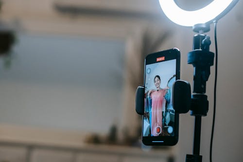 Free Faceless lady filming video on mobile while demonstrating dress Stock Photo