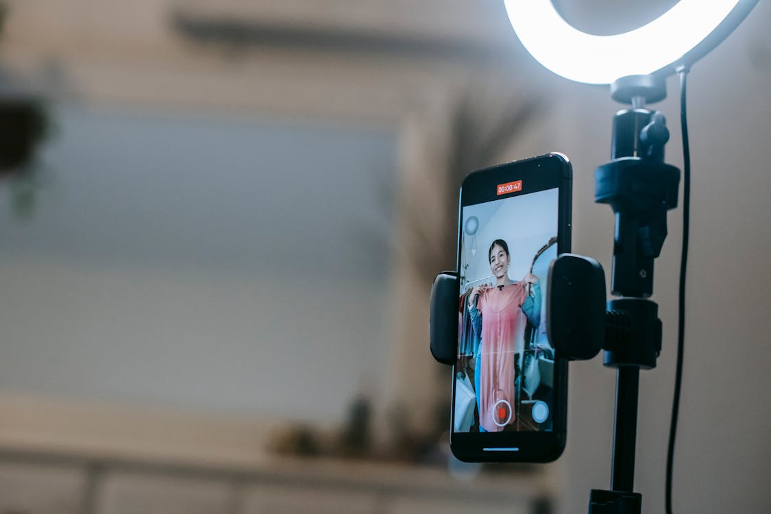 Faceless lady filming video on mobile while demonstrating dress